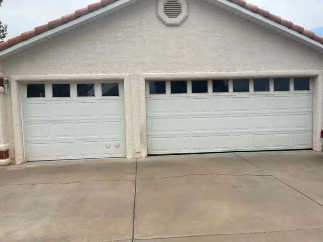 A white garage door with two windows, enhancing the aesthetic appeal of the exterior.
