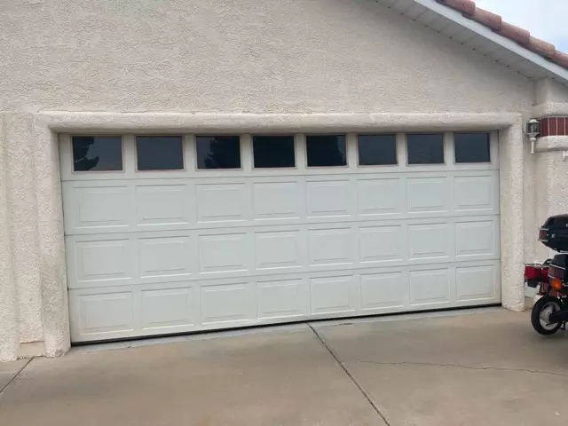 motorcycle parked in front of a Wide white garage door with windows