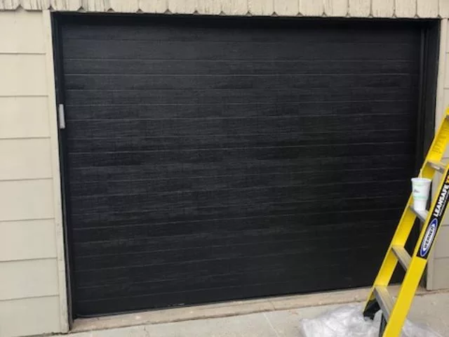 A ladder placed beside a garage door, ready for use.