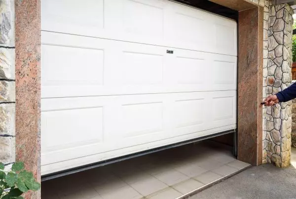 A man confidently stands before a closed garage door, exuding casual poise